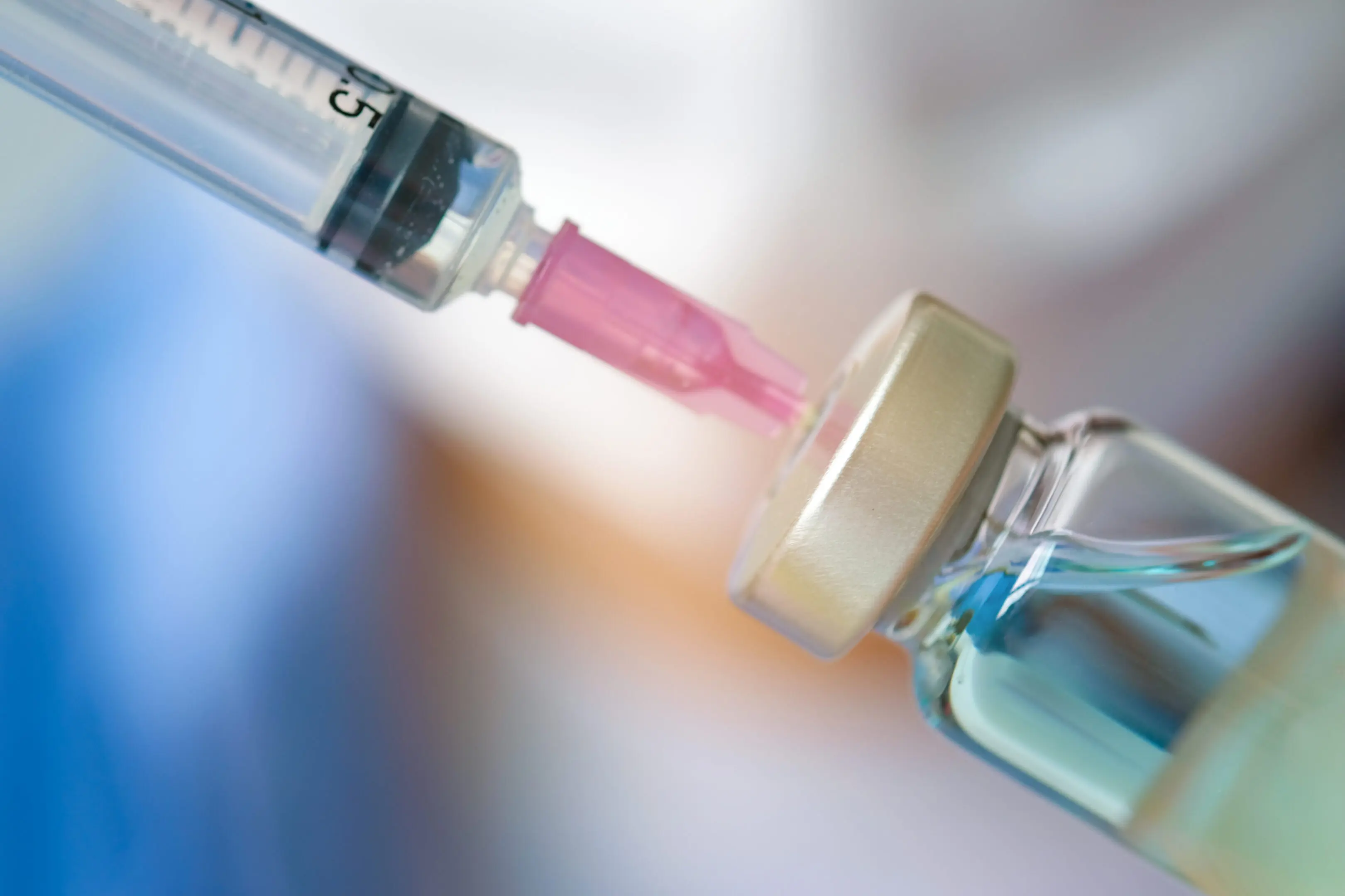 Doctor's hand holds a syringe and a blue vaccine bottle at the hospital. Health and medical concepts